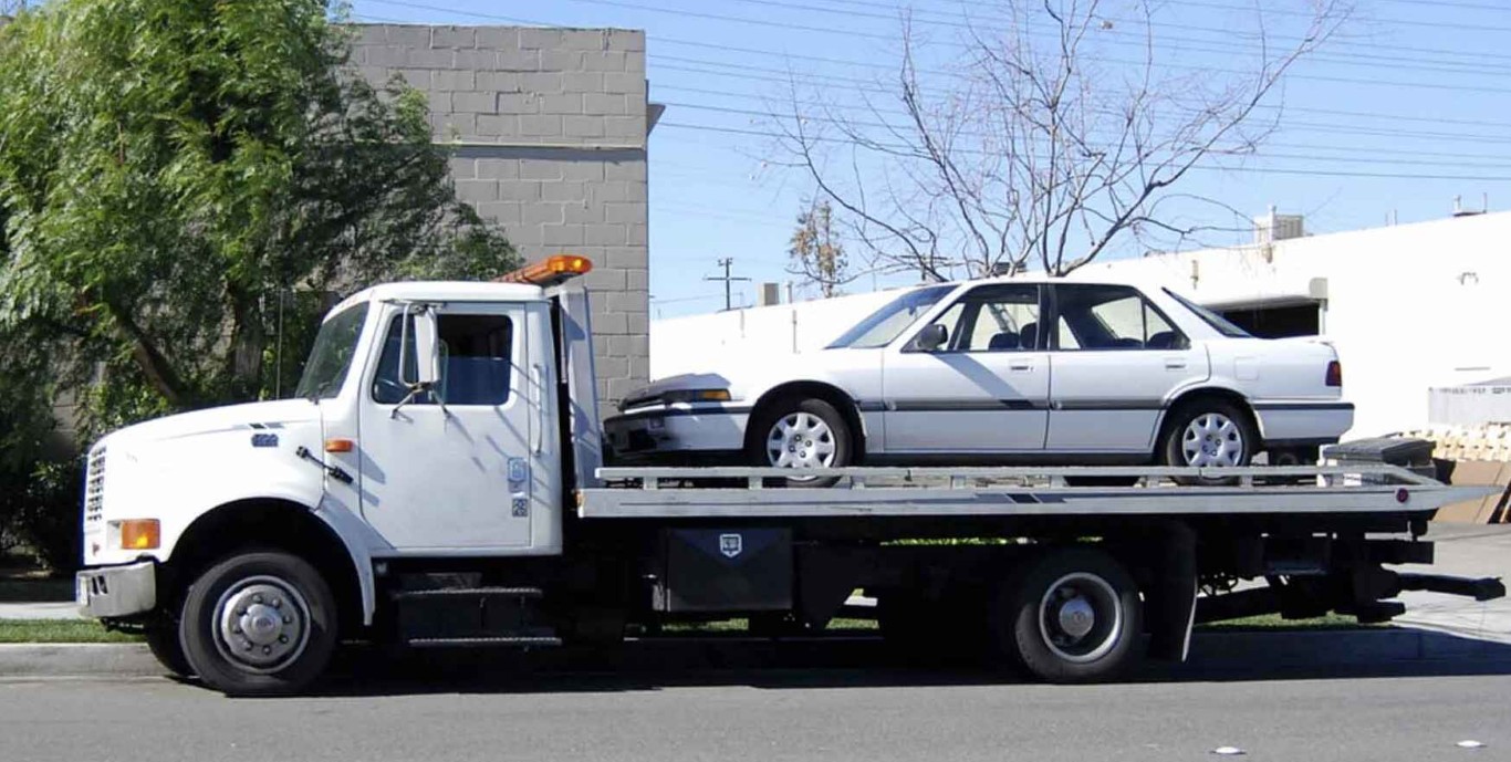 Long-distance flatbed towing service transporting vehicle safely in Syracuse, UT
